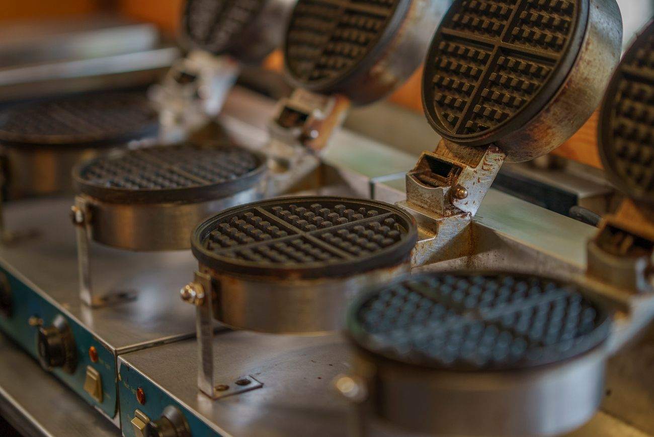 Commercial waffle irons lined up on a counter
